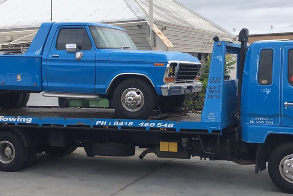 wheel lift tow truck on the back of a flat bed truck